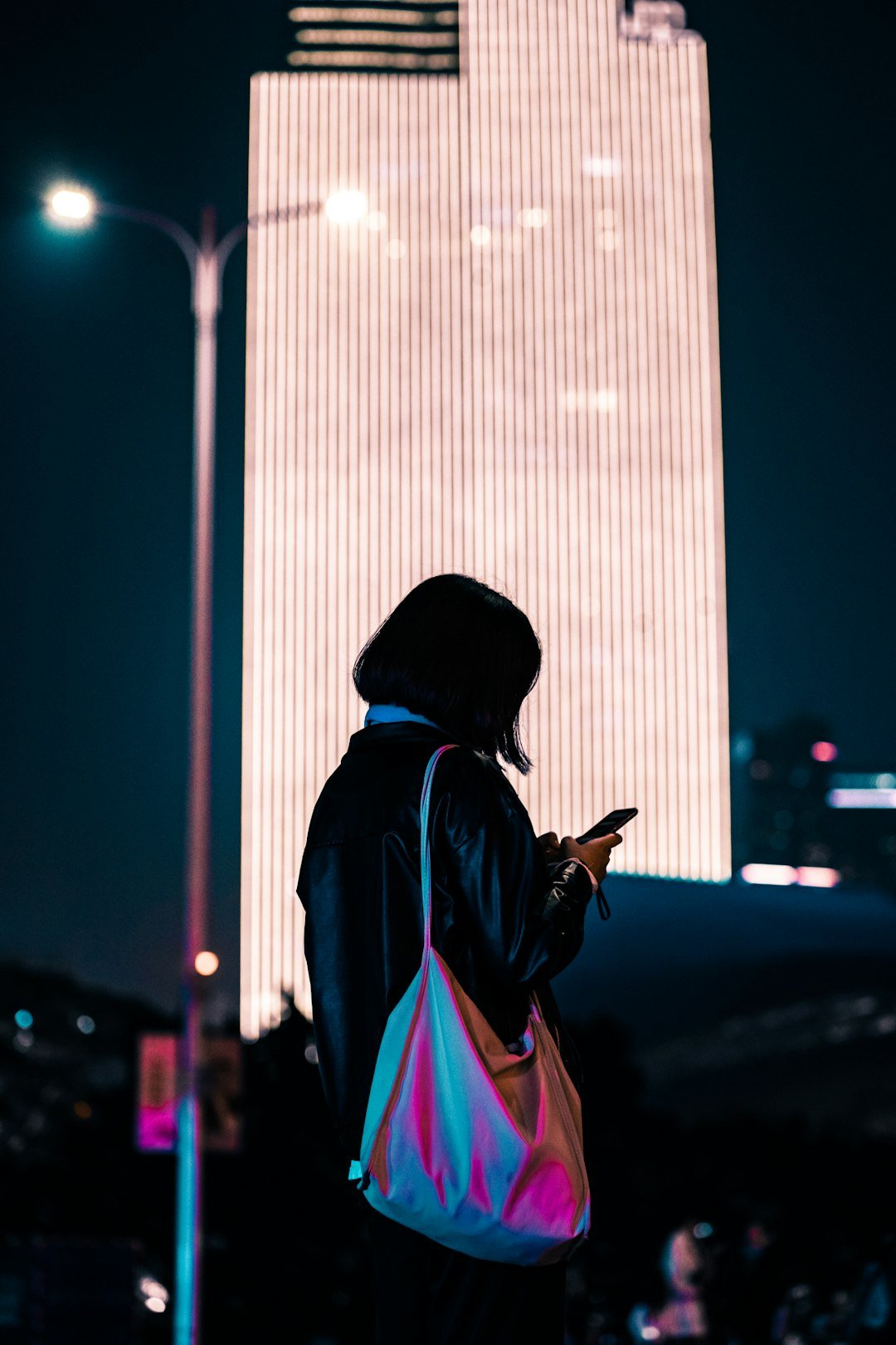 Person using a smartphone at night in an urban environment, cinematic lighting